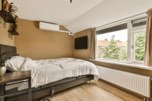 bedroom with bed desk tv mounted wall front window looking out onto street