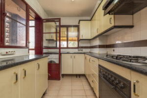 kitchen with black countertops cream cabinets gas burners some red windows door that leads drying deck