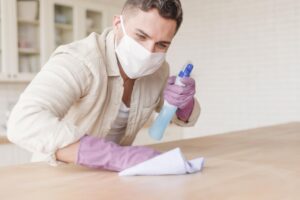 man with gloves holding disinfectant