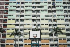 white black portable basketball hoop near tall trees concrete buildings daytime