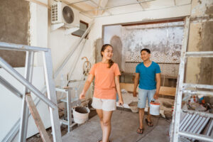 young couple walking with buckets cement renovate room