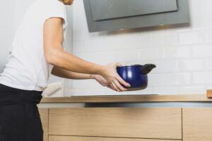 woman holding pan near cooking table