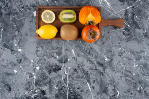 wooden board with whole sliced fresh fruits background