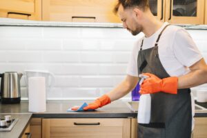 man cleaning cabinet with rag